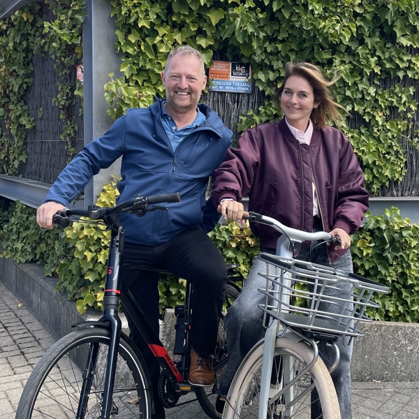 Two people pose with bike in front of bike rack